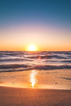 Experience the serene sunset over Ludington Beach with vibrant colors and tranquil waves.